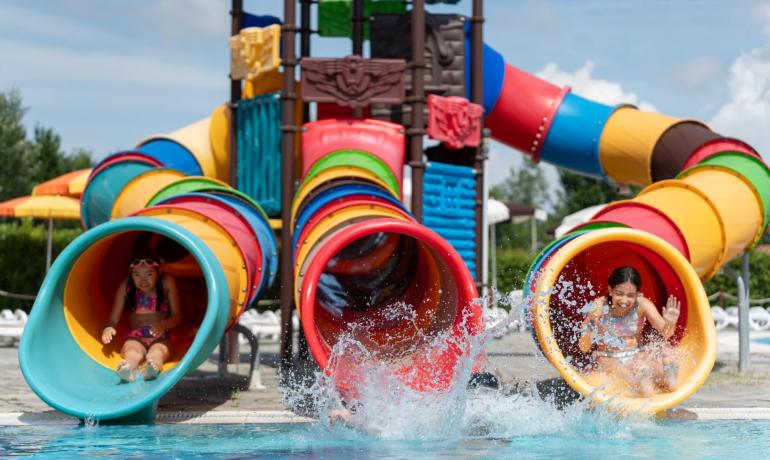 Bambini si divertono sugli scivoli colorati in piscina.