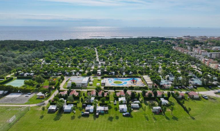 Vista aerea di un campeggio vicino al mare con piscine e vegetazione.