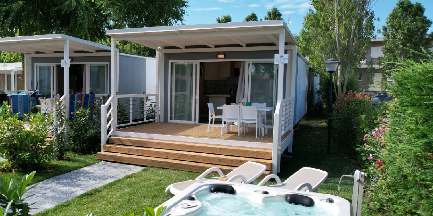 Bungalow moderni con veranda, giardino e vasca idromassaggio, immersi nel verde.