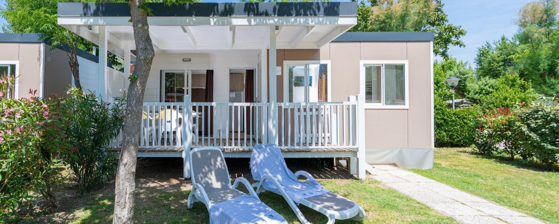 Modern bungalow met veranda en ligstoelen in de tuin.