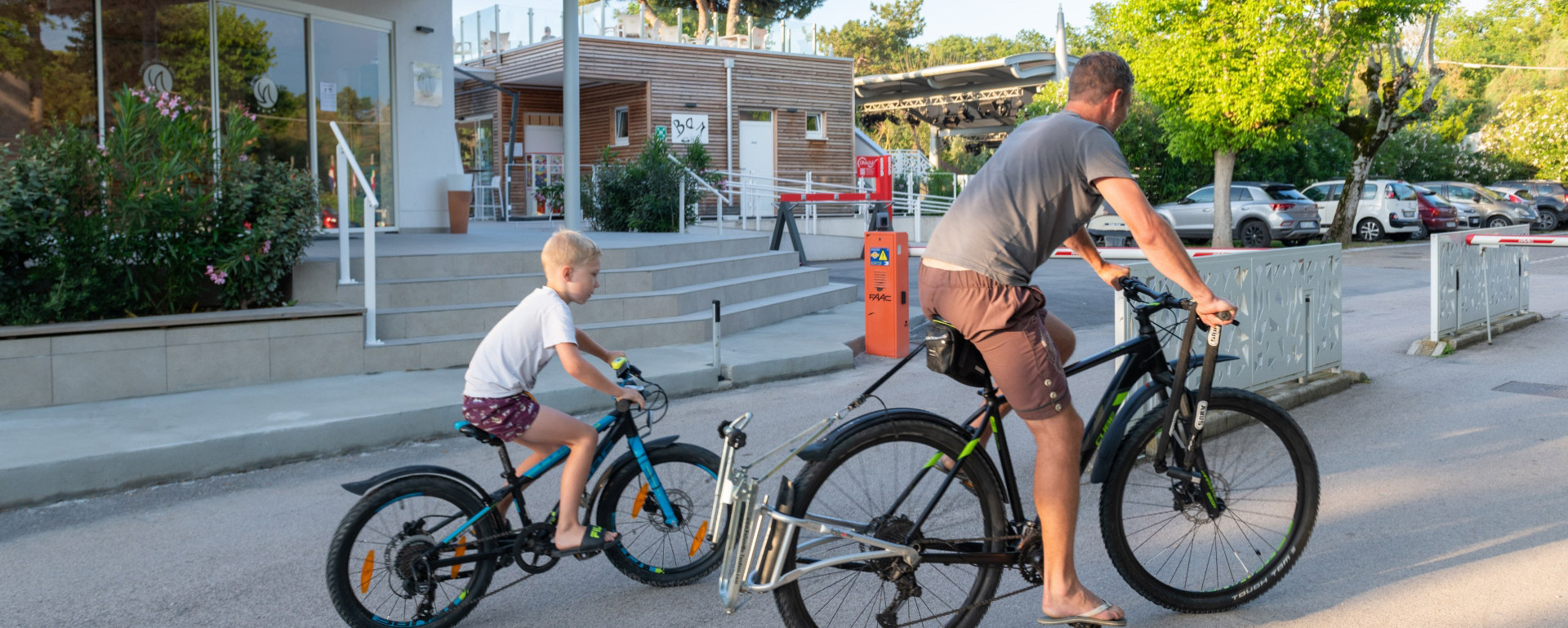 Padre e figlio in bicicletta vicino a un bar all'aperto.