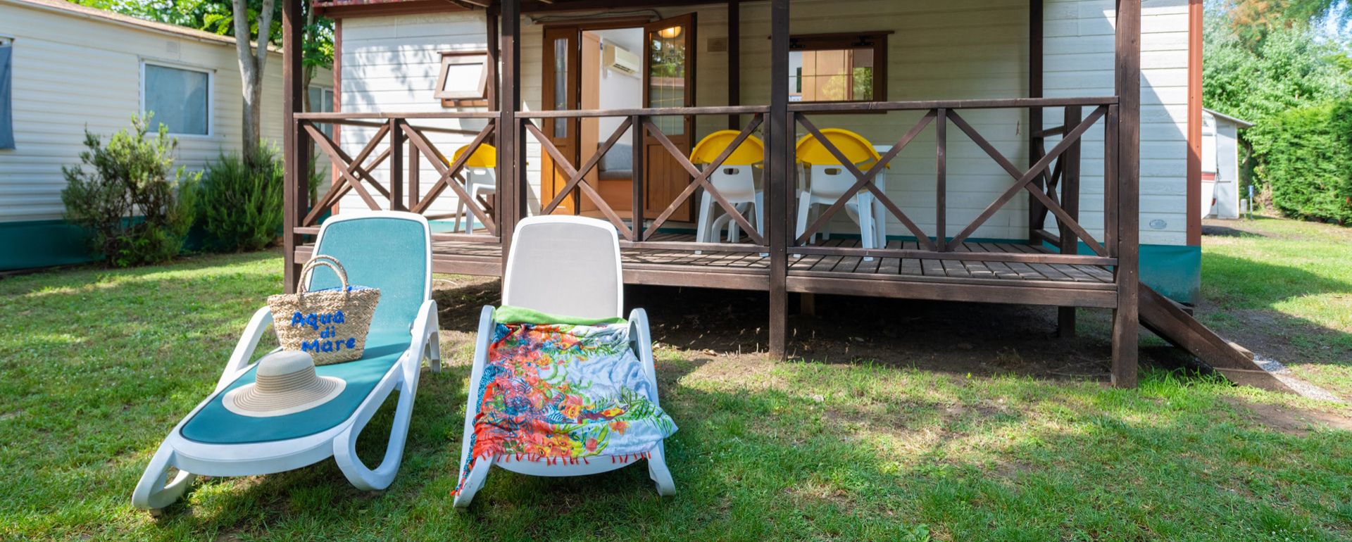 Bungalow met veranda, ligstoelen en tuin, perfect voor een ontspannen vakantie.