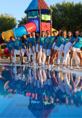 Gruppo di persone in divisa blu davanti a uno scivolo colorato, riflessi in piscina.