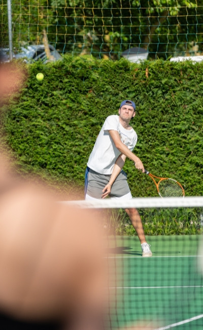 Giocatore di tennis colpisce la palla durante una partita su campo all'aperto.