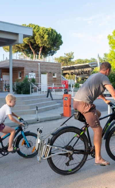 Padre e figlio pedalano insieme su biciclette davanti a un edificio moderno.