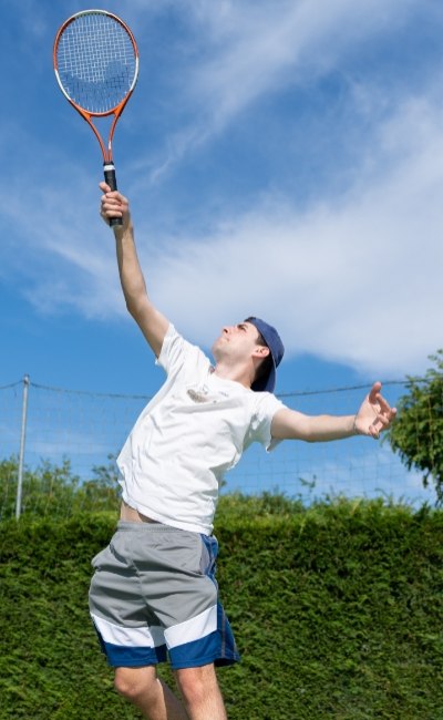 Tennisser serveert buiten op een zonnige dag.