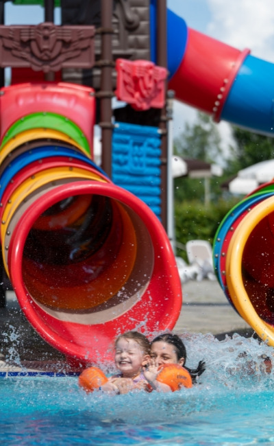 Bambini scivolano in piscina, divertimento acquatico colorato.