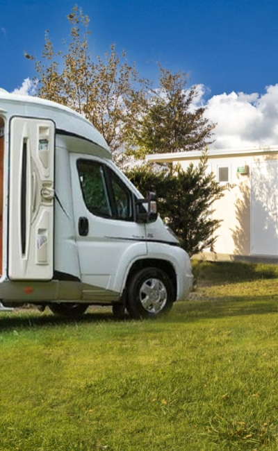 Camper parcheggiato vicino a un edificio in un'area verde.