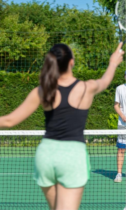 Giocatori di tennis in azione su un campo all'aperto, giornata soleggiata.