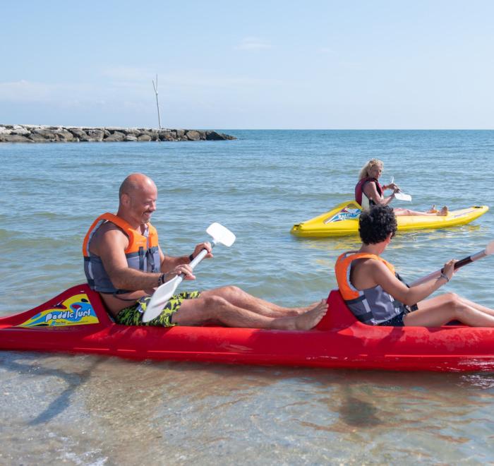 Persone in kayak colorati godono del mare in una giornata soleggiata.