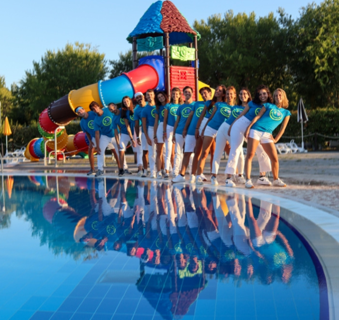 Groep mensen in blauwe uniformen bij een zwembad met een kleurrijke glijbaan.