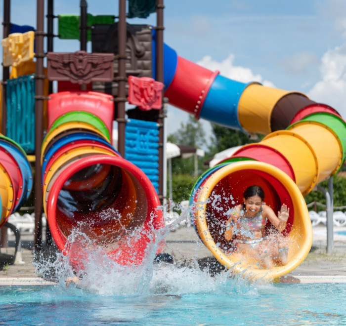 Bambini che si divertono sugli scivoli d'acqua colorati in piscina.