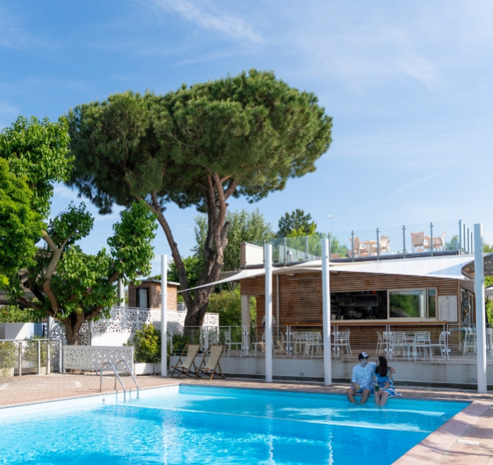 Piscina all'aperto con sedie a sdraio e bar moderno.