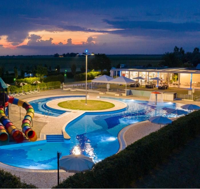 Piscina all'aperto con scivoli colorati al tramonto.