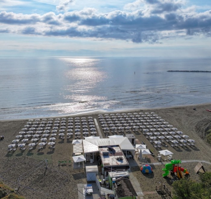 Spiaggia con ombrelloni, mare calmo e cielo nuvoloso.