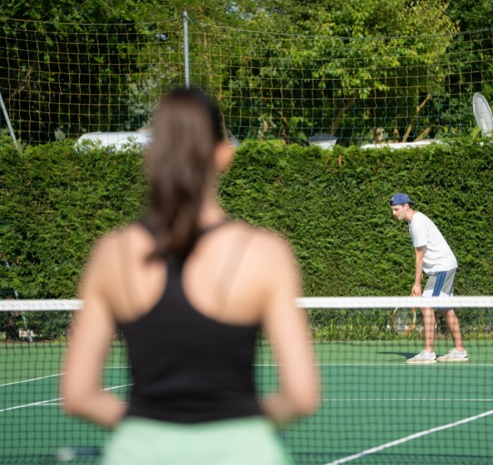 Due persone giocano a tennis su un campo all'aperto.