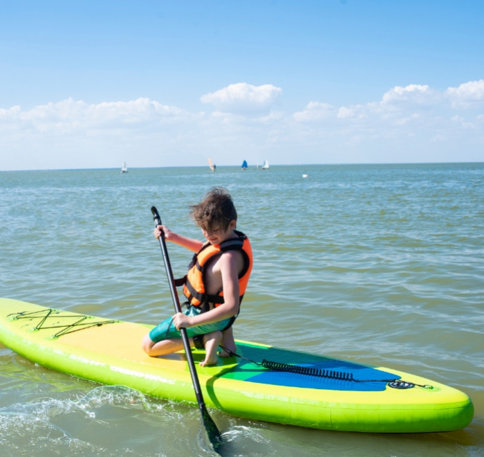 Ragazzo in canoa su acqua calma, indossa un giubbotto di salvataggio.