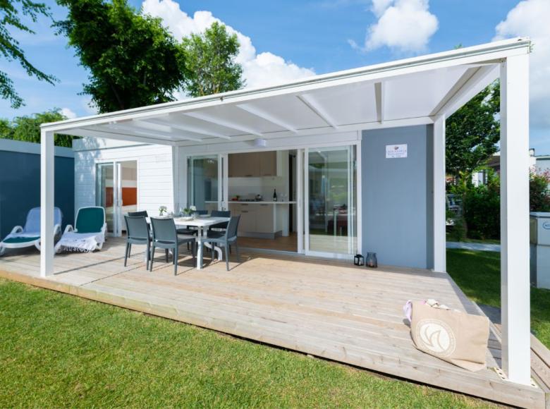 Veranda moderna con tavolo da pranzo e sedie su terrazza in legno.