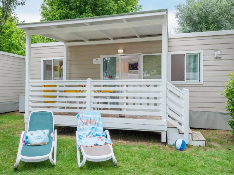 Bungalow con veranda, sdraio e pallone su prato verde, atmosfera estiva e rilassante.