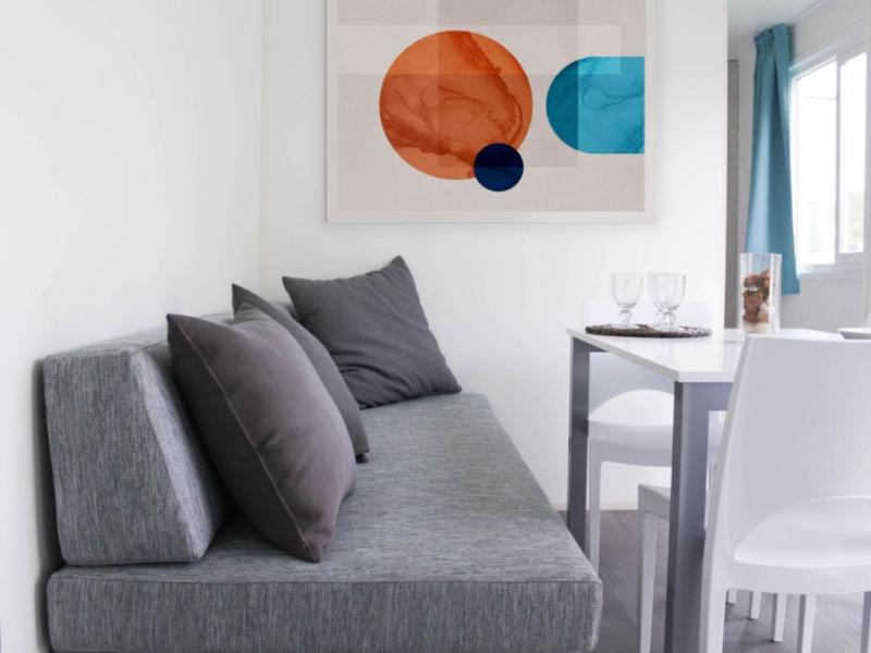 Moderne woonkamer met grijze bank en abstracte kunst.