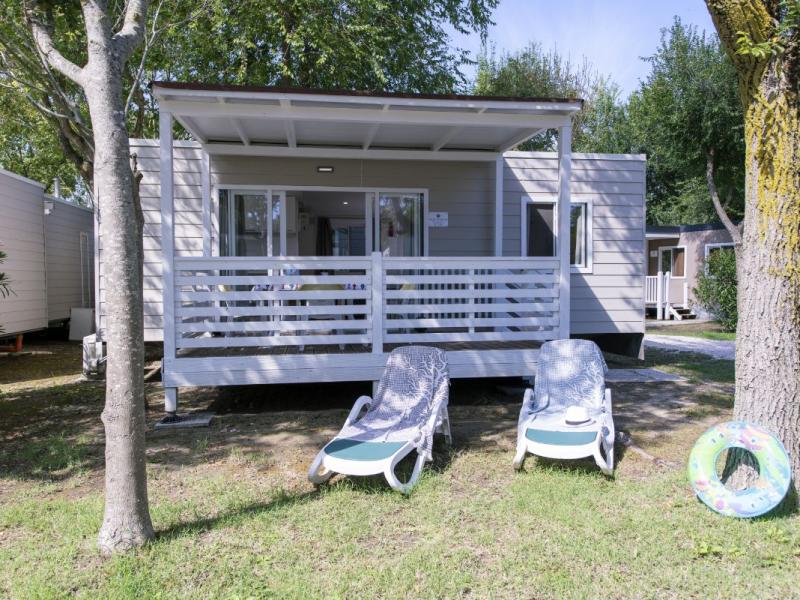 Stacaravan met veranda, ligstoelen en tuin.