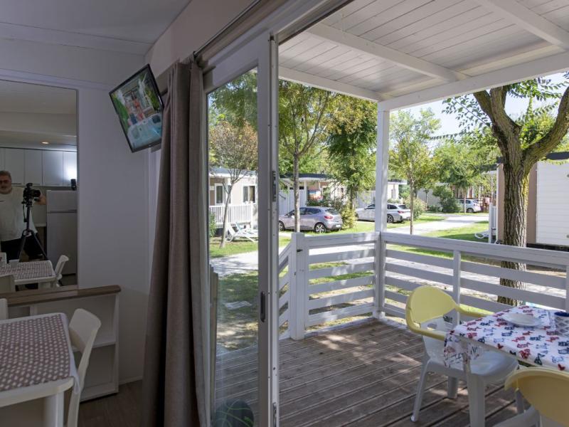 Licht interieur met terras, gedekte tafel en uitzicht op stacaravans.