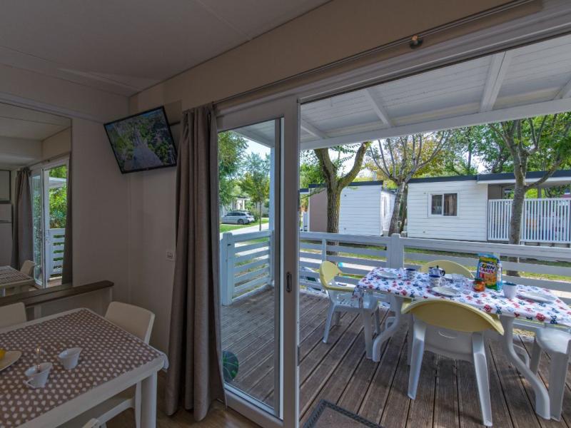 Interieur met veranda, gedekte tafel, uitzicht op stacaravans.