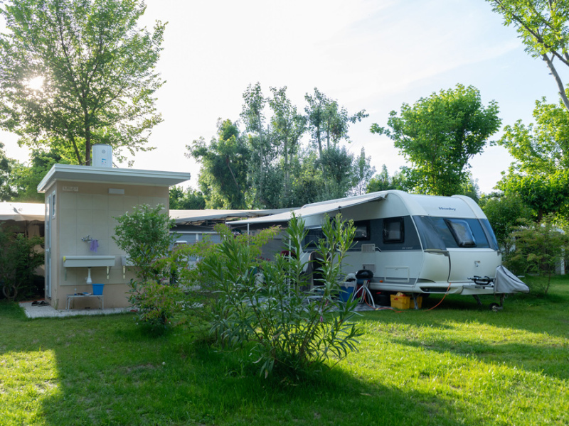 Caravan in campeggio verde con servizi esterni.