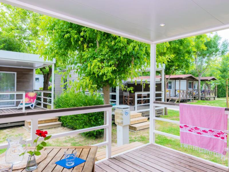 Houten veranda met uitzicht op bungalows en groene bomen.