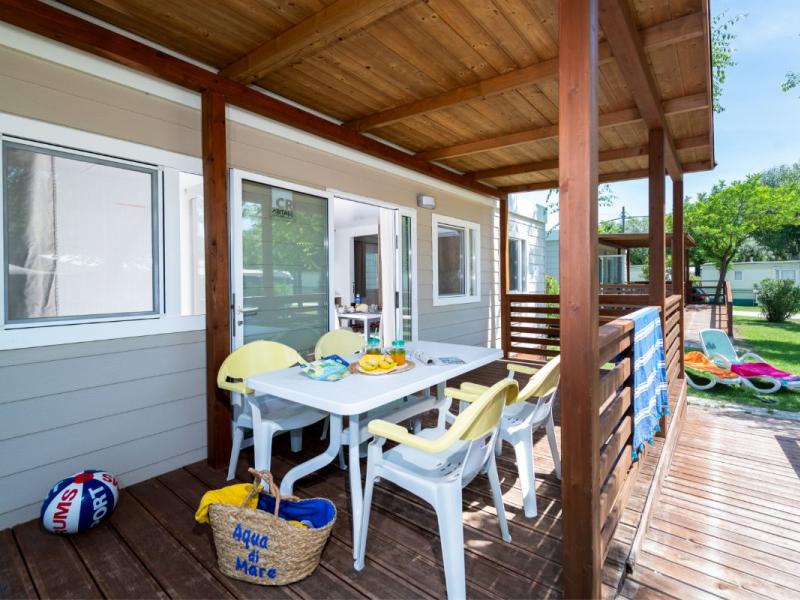 Zomerterras met tafel en stoelen, omgeven door groen.